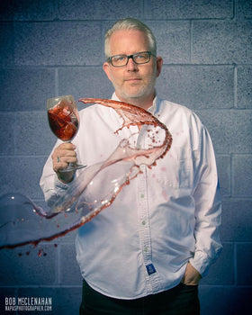 Christian Oggenfuss holding a wine glass as a swirl of red wine arcs through the air