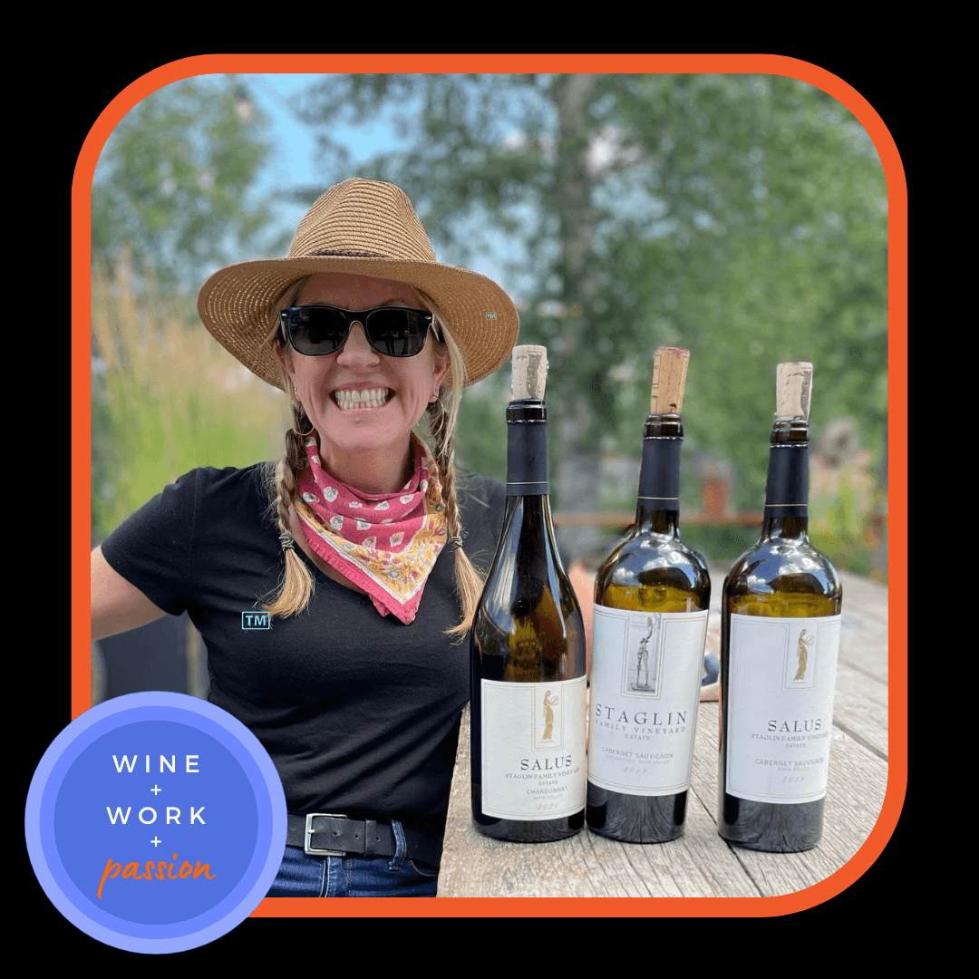 Napa Valley Wine Academy Wine Articles  A woman wearing a hat and sunglasses smiles at the camera, with several wine bottles placed on a table in the background.