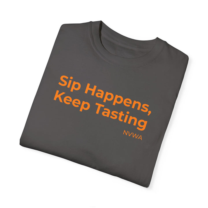 NVWA T-shirt “Sip Happens, Keep Tasting” featuring orange text on a grey background, ideal for wine enthusiasts, offering a relaxed fit and durable stitching.