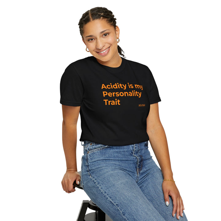 Woman smiling, wearing NVWA T-shirt “Acidity is my Personality Trait,” sitting on a stool, showcasing the shirt's relaxed fit and crew neckline.