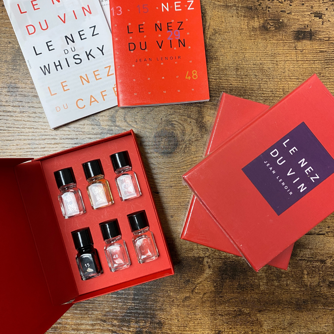 6 Wine Aroma – Introductory Kit | Le Nez du Vin: Six small bottles in a red box next to books, ideal for wine tasting and aroma identification.